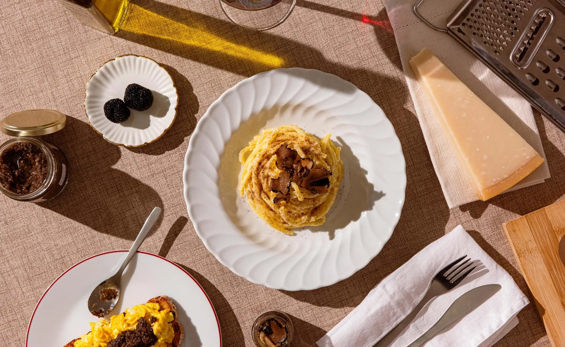Tonnarelli al tartufo nero fresco, composizione editoriale con tartufi interi, parmigiano e olio Alvitius